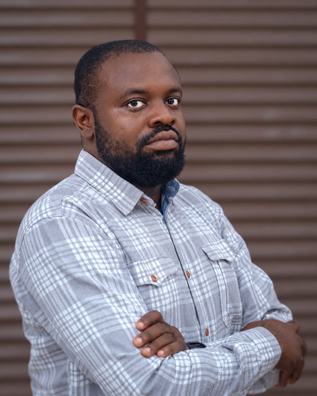 Femi Fragile, arms folded, in a grey checked shirt